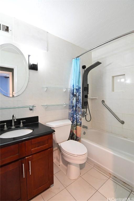 full bathroom with tile patterned floors, toilet, tile walls, vanity, and shower / bath combo