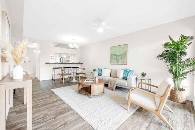 living room featuring hardwood / wood-style flooring, sink, and ceiling fan with notable chandelier