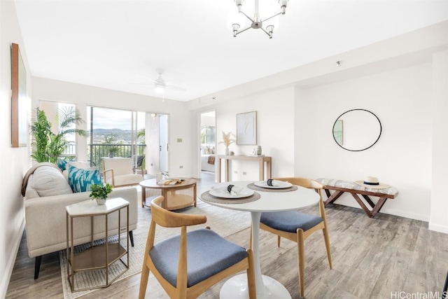 dining area featuring ceiling fan with notable chandelier and light hardwood / wood-style flooring