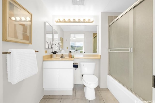 full bathroom featuring combined bath / shower with glass door, tile patterned flooring, vanity, ceiling fan, and toilet