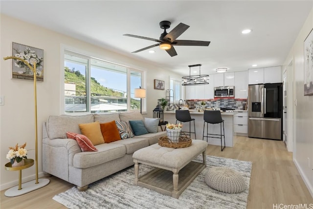 living room with light hardwood / wood-style flooring and ceiling fan