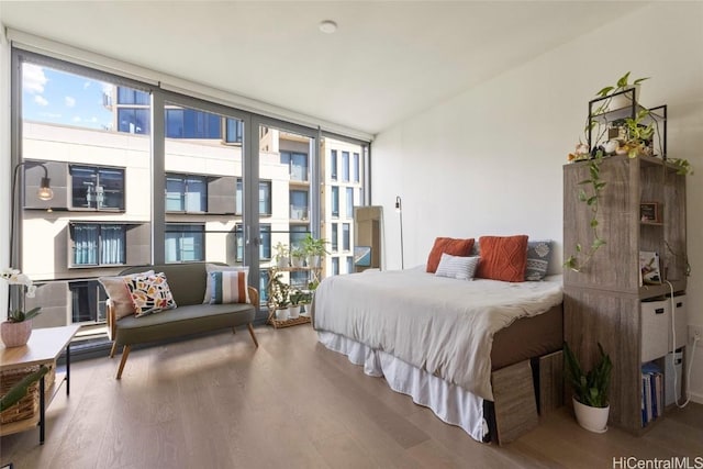 bedroom with a wall of windows and wood-type flooring