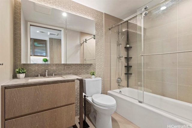 full bathroom featuring tile walls, bath / shower combo with glass door, tasteful backsplash, vanity, and toilet