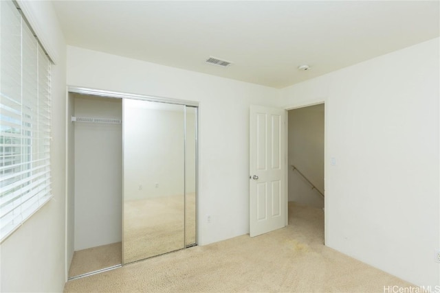 unfurnished bedroom featuring a closet, carpet floors, and visible vents