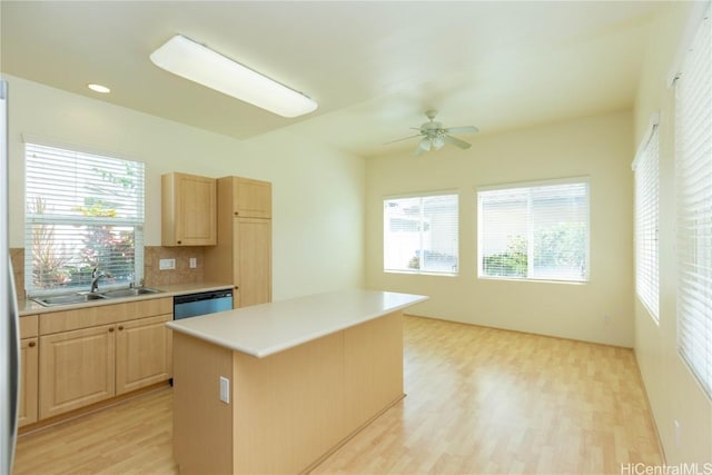 kitchen with a sink, dishwasher, light brown cabinetry, and light countertops