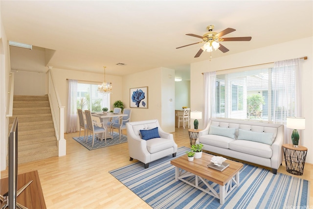 living room with stairway, ceiling fan with notable chandelier, wood finished floors, and visible vents