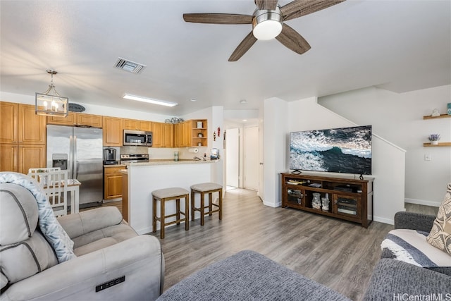 living room featuring light wood-type flooring, ceiling fan, visible vents, and baseboards