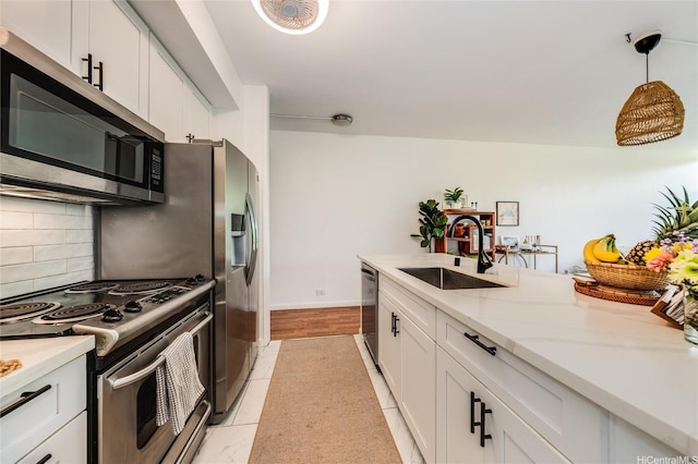 kitchen featuring a sink, stainless steel appliances, backsplash, and white cabinetry