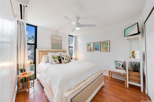 bedroom featuring wood finished floors, a ceiling fan, and multiple windows