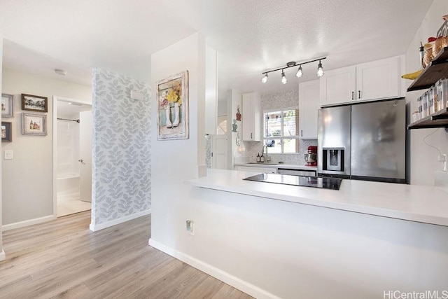 kitchen with white cabinetry, sink, stainless steel fridge, light hardwood / wood-style floors, and black electric cooktop