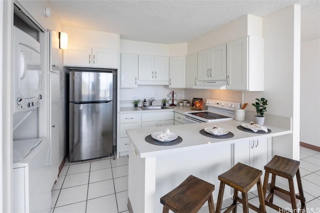 kitchen with sink, white electric range, stainless steel refrigerator, white cabinetry, and kitchen peninsula