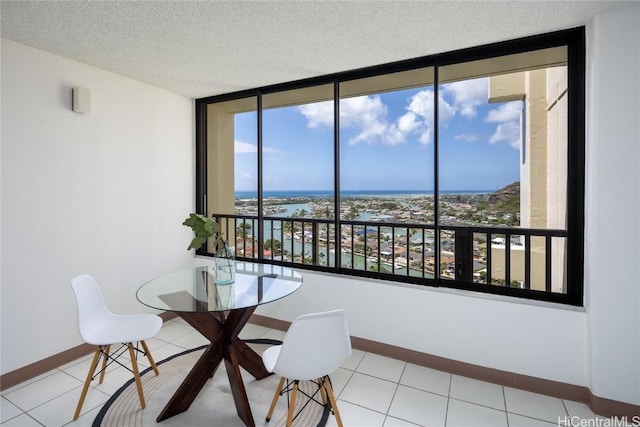 dining area with a water view, a textured ceiling, and light tile patterned floors