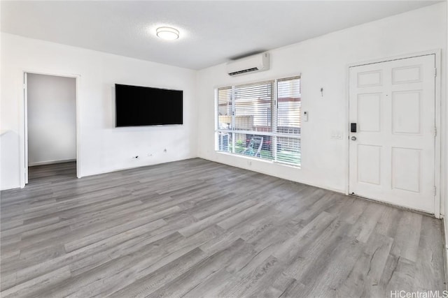 unfurnished living room featuring wood finished floors and a wall mounted AC