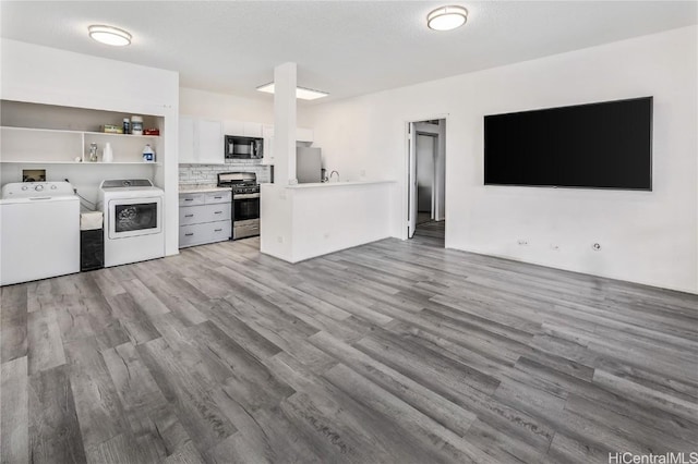 kitchen featuring open floor plan, refrigerator, stainless steel gas range, black microwave, and separate washer and dryer