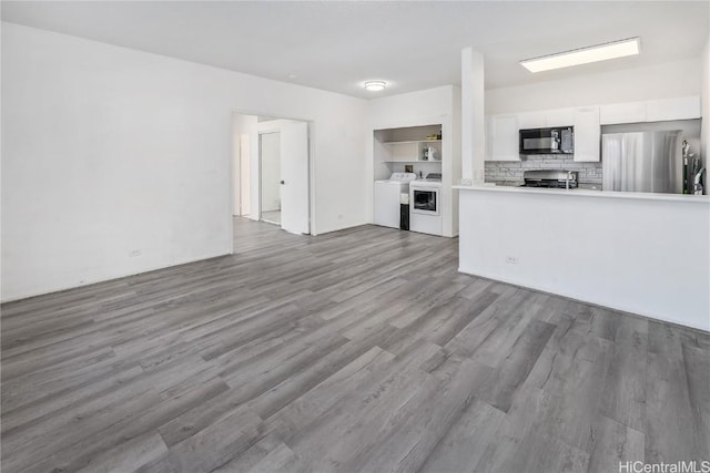 unfurnished living room with washing machine and dryer and wood finished floors