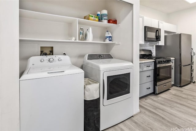 laundry area with light wood-type flooring, laundry area, and washer and clothes dryer