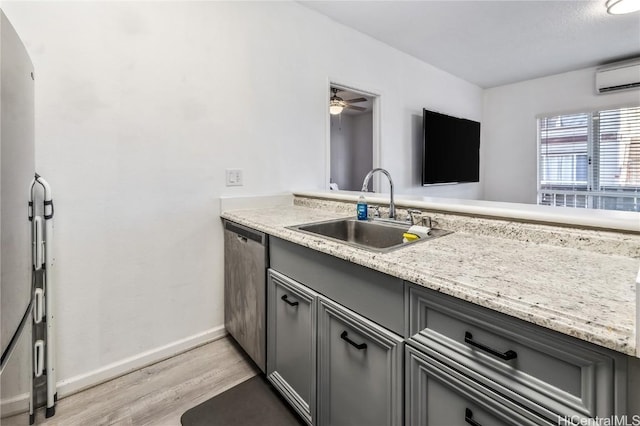 kitchen featuring a wall unit AC, light wood-style flooring, a sink, gray cabinets, and dishwasher