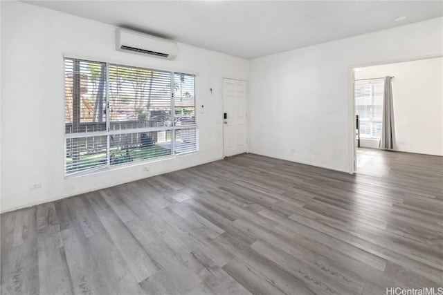 unfurnished room with a wall unit AC and wood finished floors