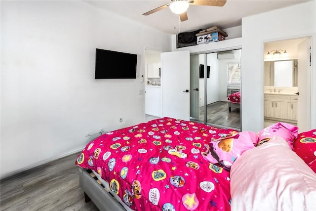 bedroom featuring a closet, a ceiling fan, a sink, ensuite bath, and wood finished floors