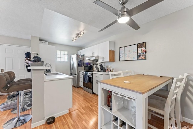 kitchen featuring a breakfast bar, sink, white cabinets, kitchen peninsula, and stainless steel appliances