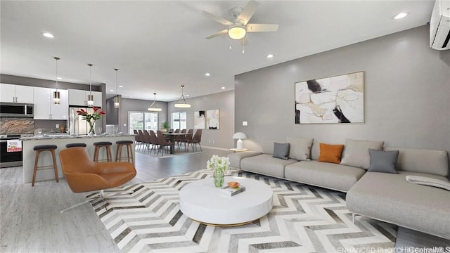 living room with ceiling fan, a wall mounted AC, and light hardwood / wood-style floors