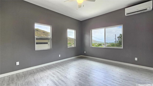 empty room featuring ceiling fan, light wood-type flooring, and a wall unit AC