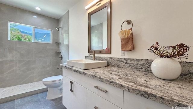 bathroom featuring vanity, a tile shower, and toilet