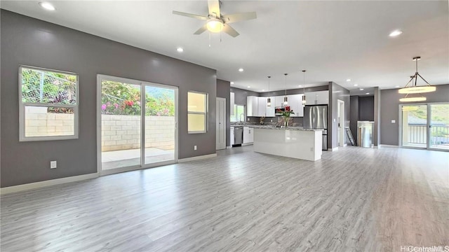 unfurnished living room with sink, ceiling fan, and light hardwood / wood-style flooring