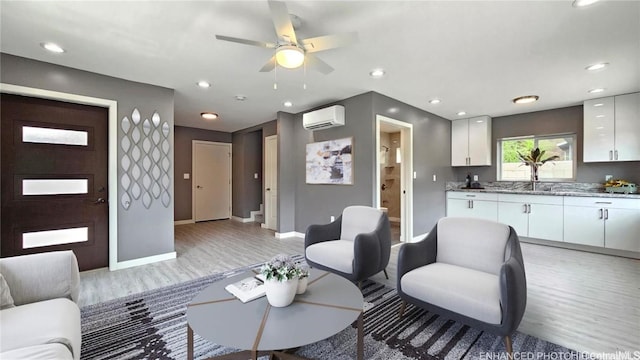 living room with a wall mounted air conditioner, light hardwood / wood-style flooring, and ceiling fan