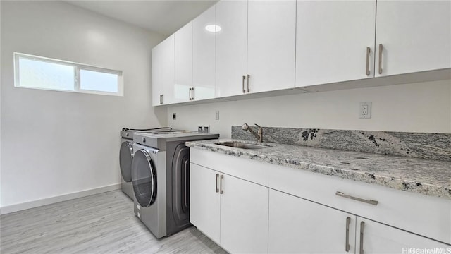 washroom featuring cabinets, washer and dryer, sink, and light wood-type flooring