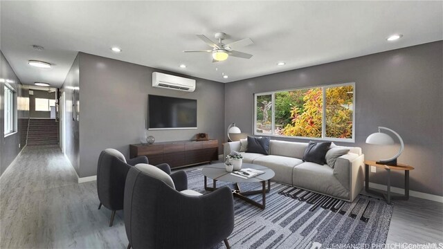 living room featuring hardwood / wood-style flooring, ceiling fan, and a wall unit AC