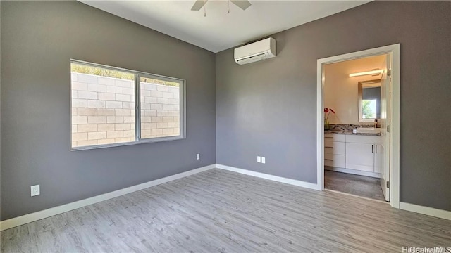 spare room featuring ceiling fan, a wall mounted AC, and light wood-type flooring