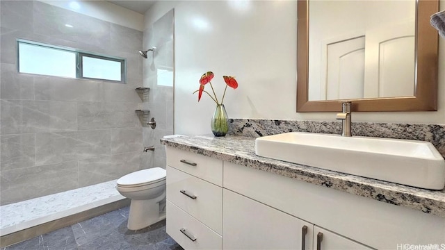 bathroom with vanity, toilet, and a tile shower