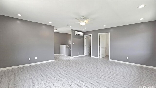 spare room featuring ceiling fan, light hardwood / wood-style floors, and an AC wall unit