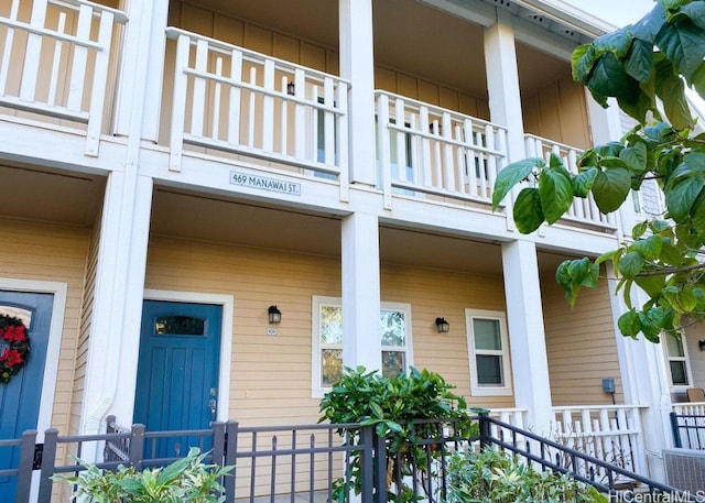 entrance to property with central AC unit, board and batten siding, a porch, and a balcony