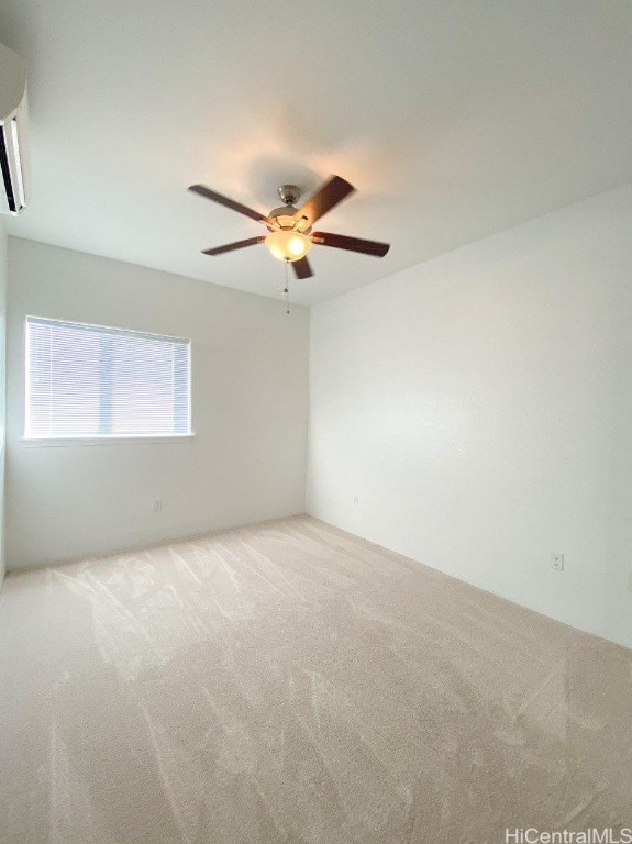 spare room with ceiling fan, carpet, and a wall mounted air conditioner