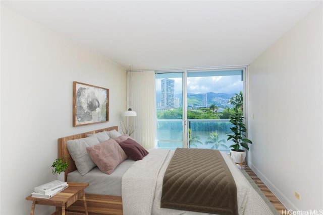 bedroom with wood-type flooring, floor to ceiling windows, and access to outside