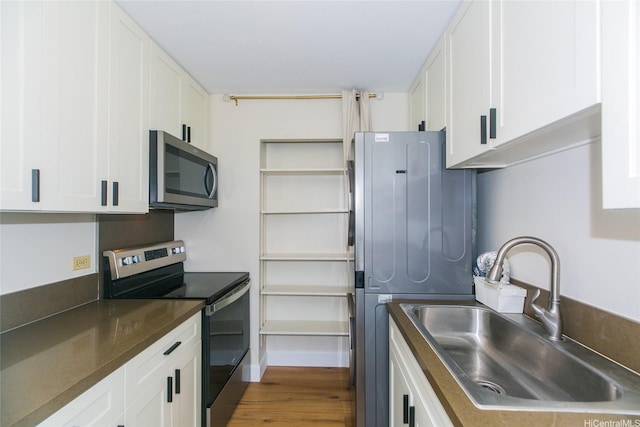 2233 Ala Wai Blvd Unit 5B, Honolulu, HI 96815 - kitchen with stainless steel appliances, wood finished floors, a sink, and white cabinetry