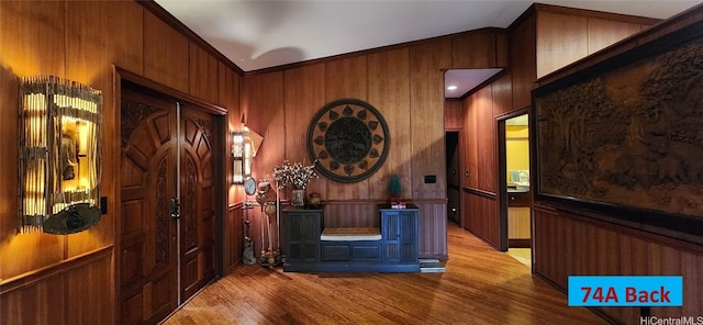 hallway with light wood-style floors, a wainscoted wall, and crown molding