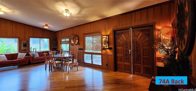 dining room with hardwood / wood-style flooring, lofted ceiling, and wooden walls