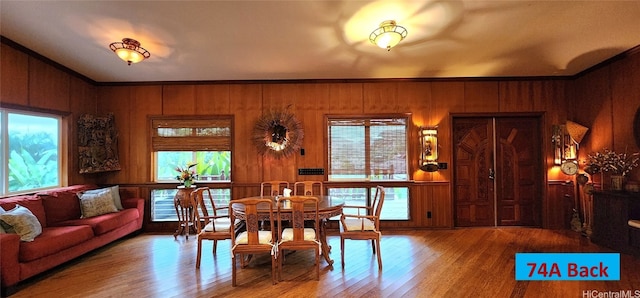 dining space with crown molding, wood finished floors, and wooden walls