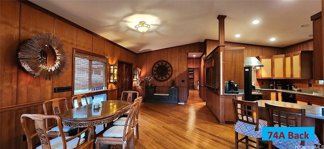 dining area featuring crown molding, lofted ceiling, light hardwood / wood-style floors, and wood walls