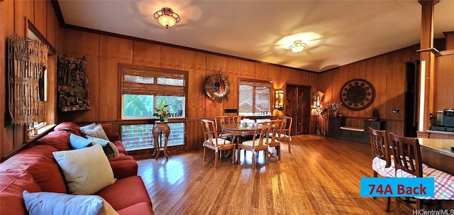 dining area featuring ornamental molding, light hardwood / wood-style floors, and wood walls