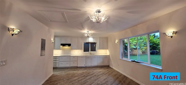 kitchen with white dishwasher, wood finished floors, a sink, white cabinetry, and light countertops