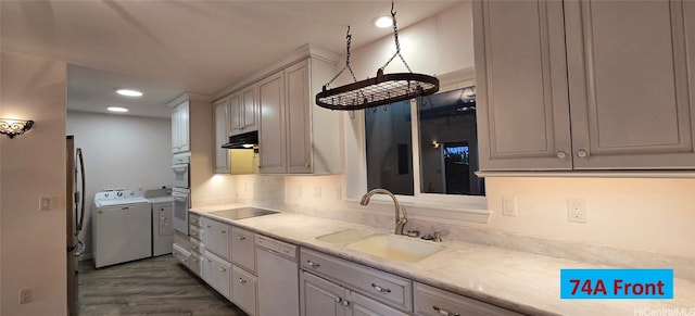 kitchen featuring dishwasher, sink, washer and clothes dryer, light stone countertops, and black electric cooktop