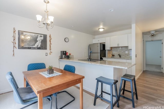 kitchen featuring sink, white cabinets, stainless steel fridge, decorative backsplash, and kitchen peninsula