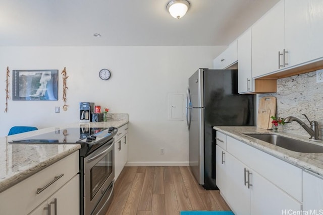 kitchen featuring sink, white cabinetry, appliances with stainless steel finishes, light hardwood / wood-style floors, and backsplash