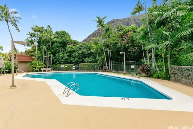 community pool featuring a patio area, fence, and a mountain view