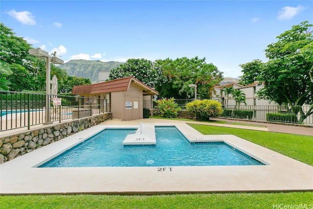 pool featuring fence, a mountain view, and an outdoor structure