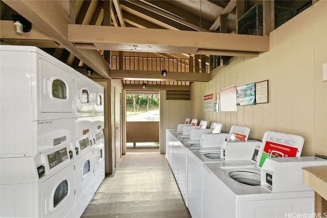 shared laundry area featuring stacked washing maching and dryer, washer and clothes dryer, light wood-style floors, and wood walls